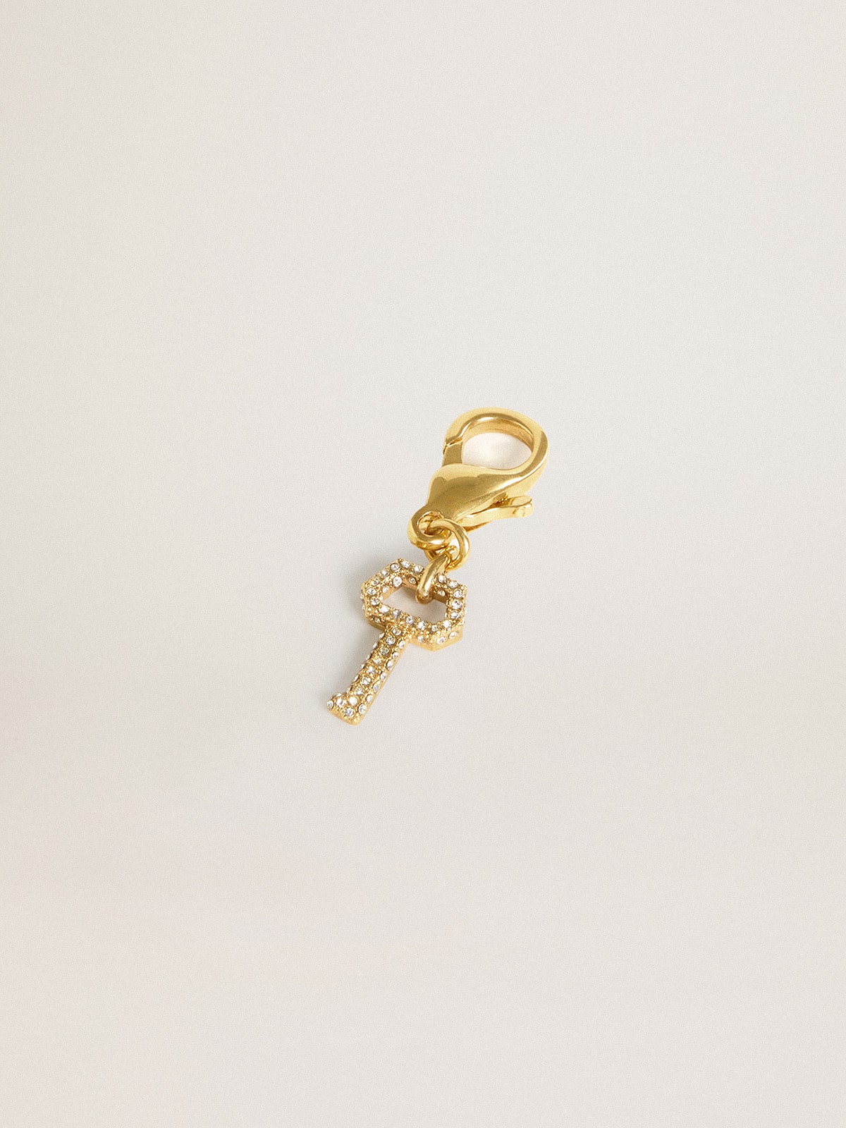 Key-shaped charm in gold-colored brass with crystals
